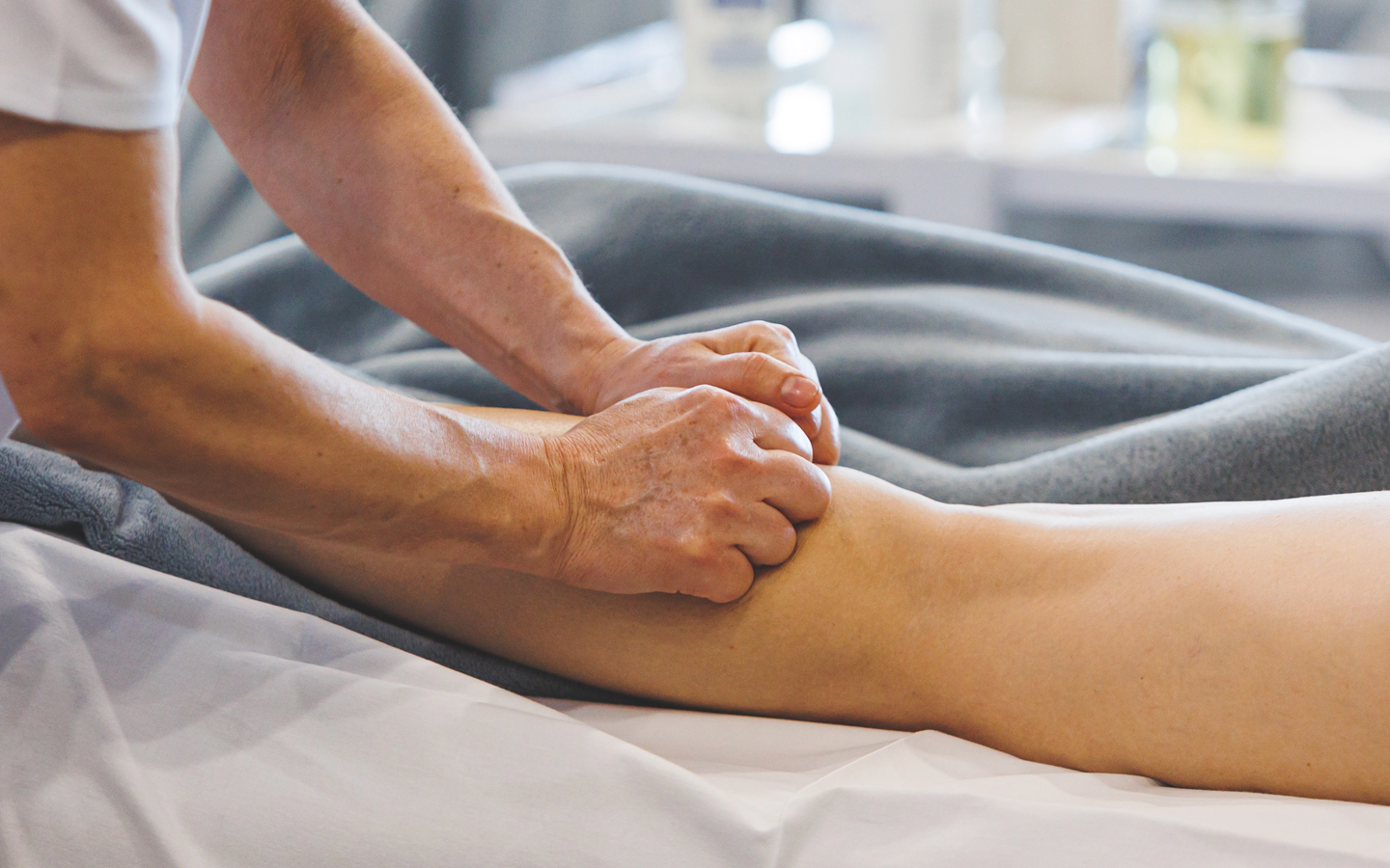 Massage therapist pressing a client’s lower leg on a treatment table