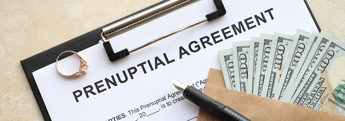 Prenuptial agreement document with pen, dollar bills, and a gavel on a desk