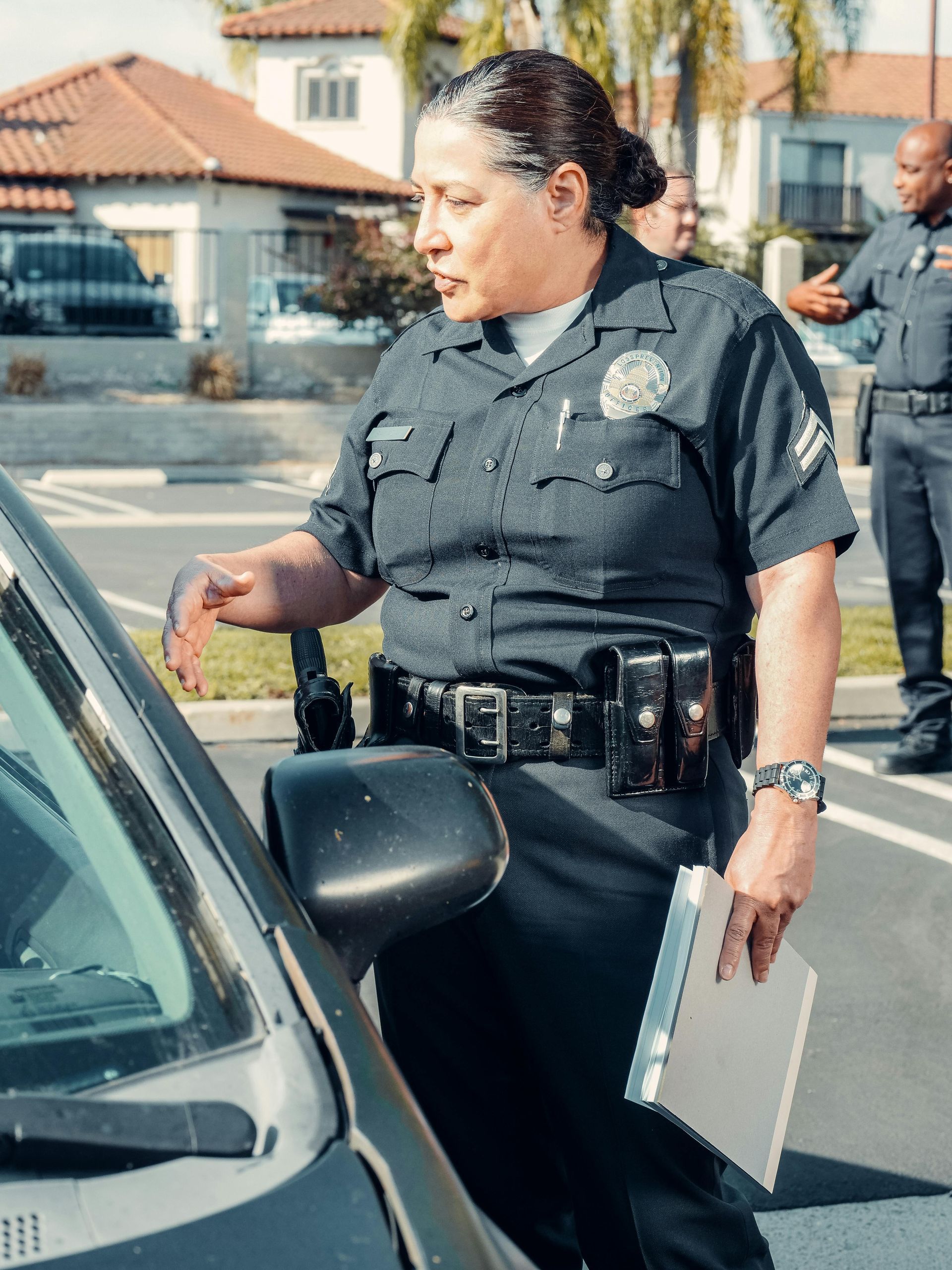 Police officer speaking to a driver beside a car on a residential street