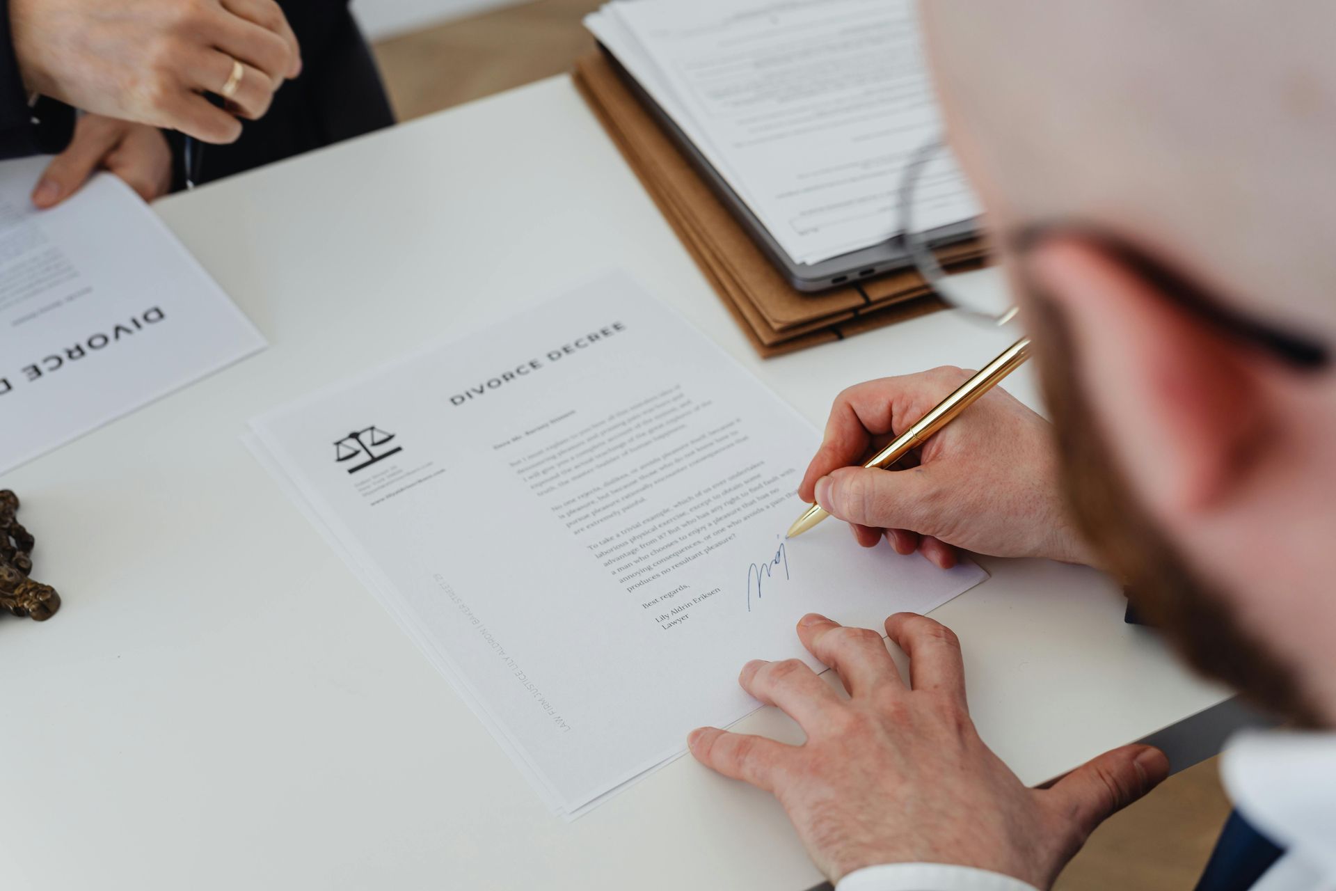 Hands reviewing and signing documents at a desk with papers and a notebook