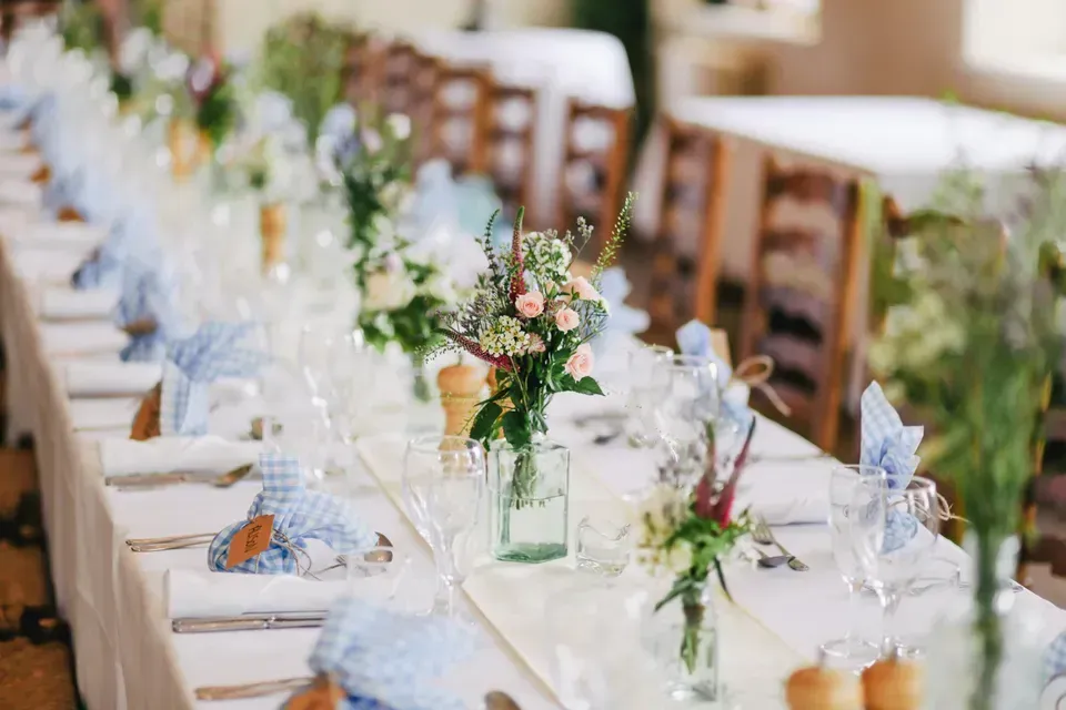 A long table is set for a party with flowers in vases on it