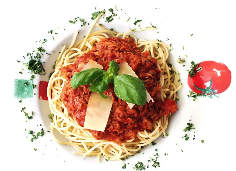 A plate of spaghetti with tomato sauce and basil on top