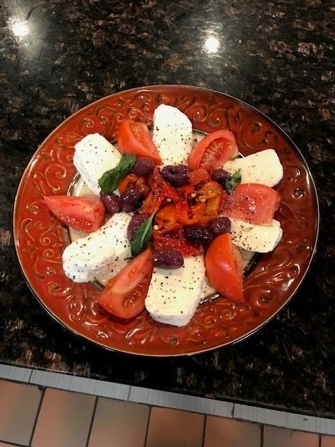 A plate of tomatoes, olives and cheese on a table