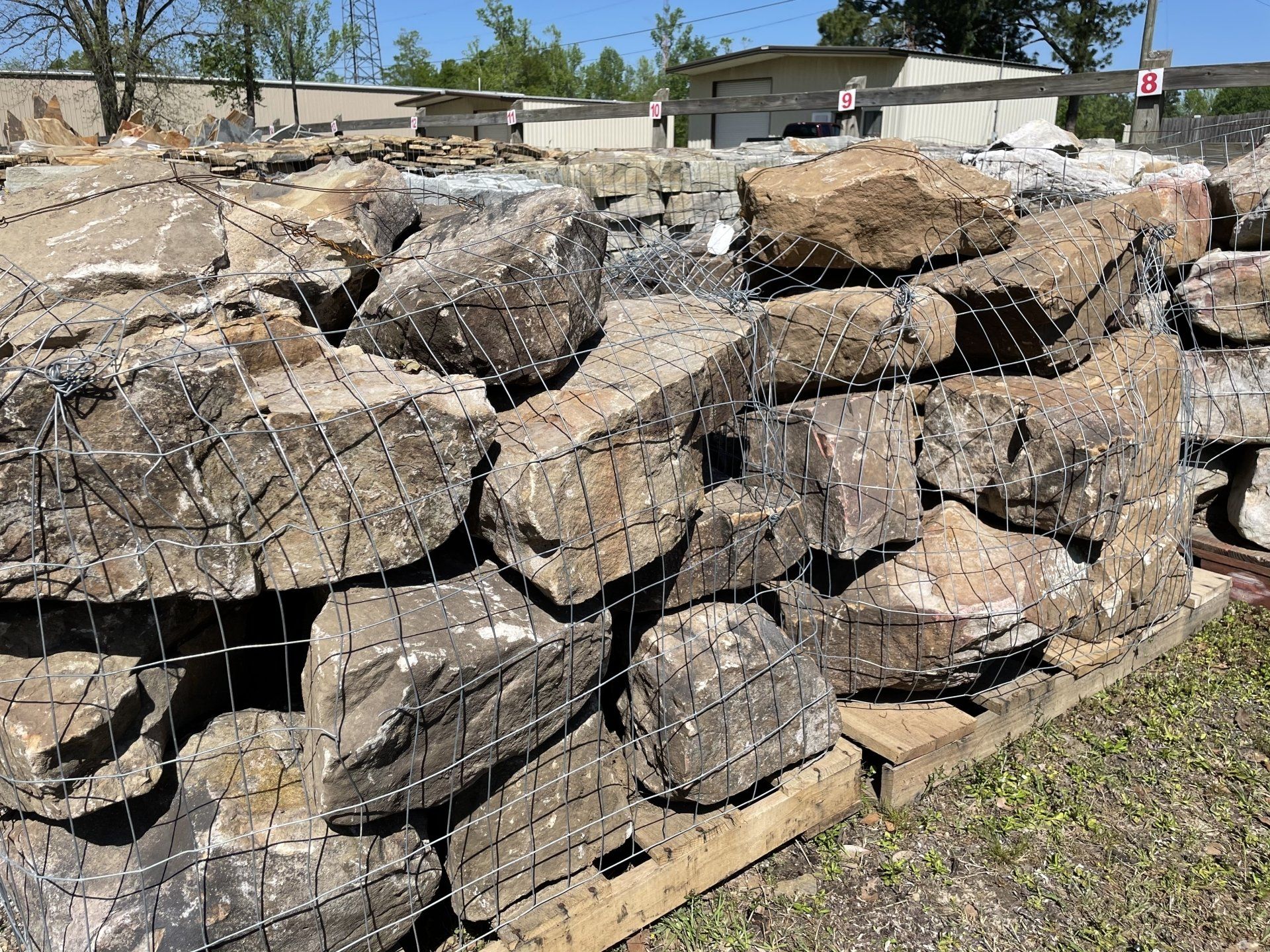 Large rocks in a wire mesh container at a landscaping supply store.