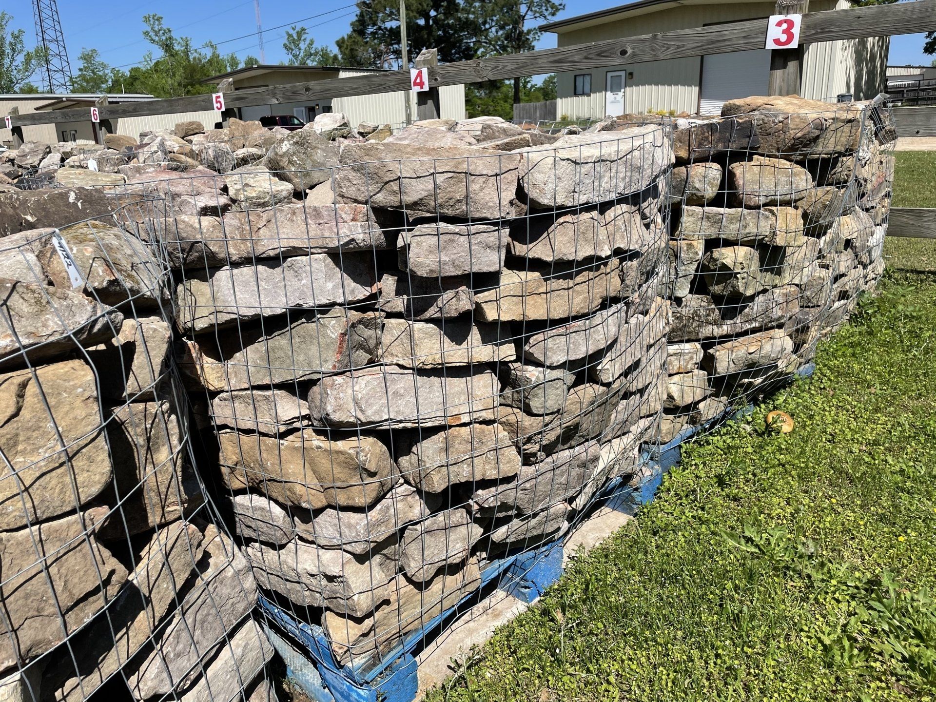Stone blocks in wire mesh cages stacked on pallets outside.