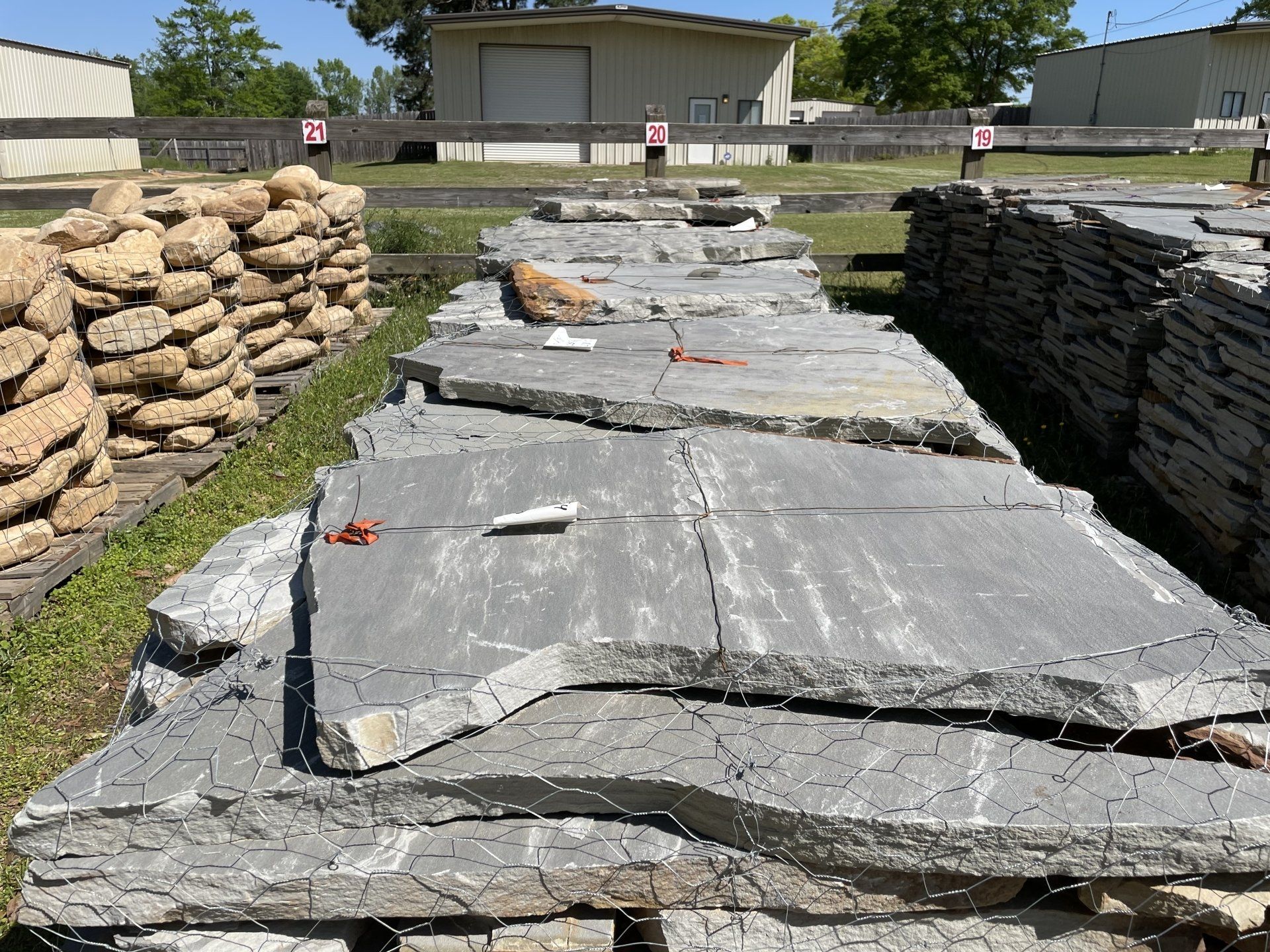 Stacks of gray flagstone for sale at an outdoor landscaping supply store.
