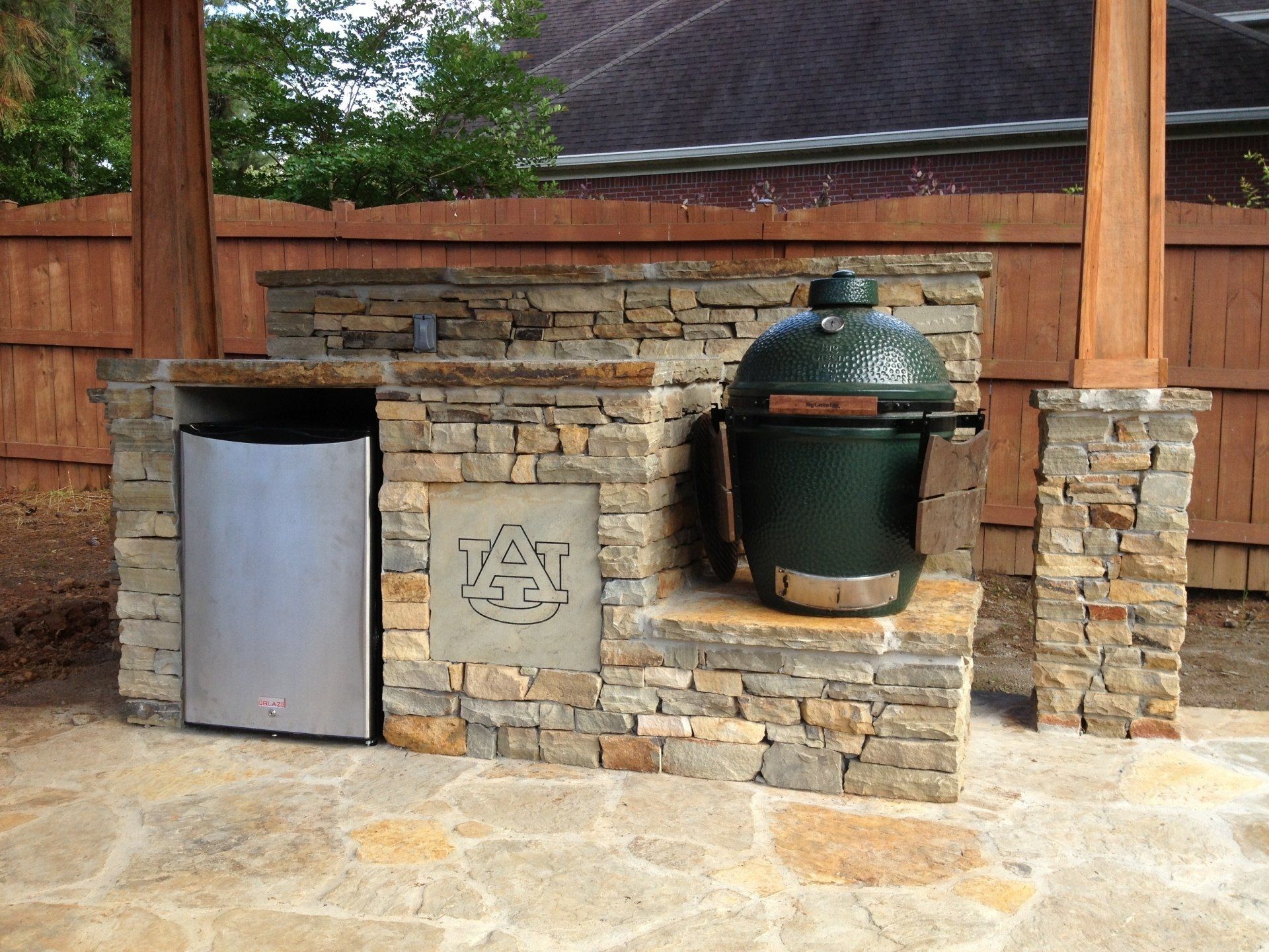 A green egg grill is built into a stone wall