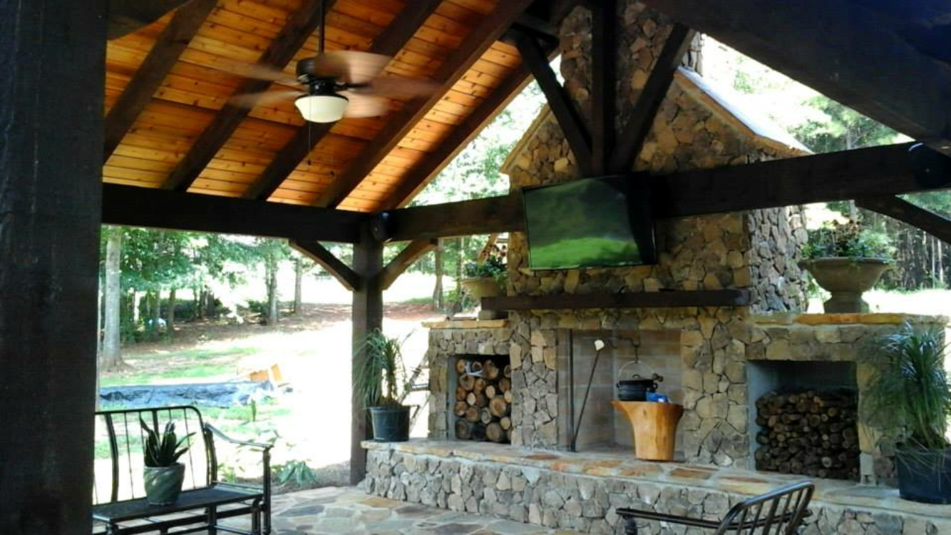 Outdoor patio with a stone fireplace, wood-beamed ceiling, and seating area.