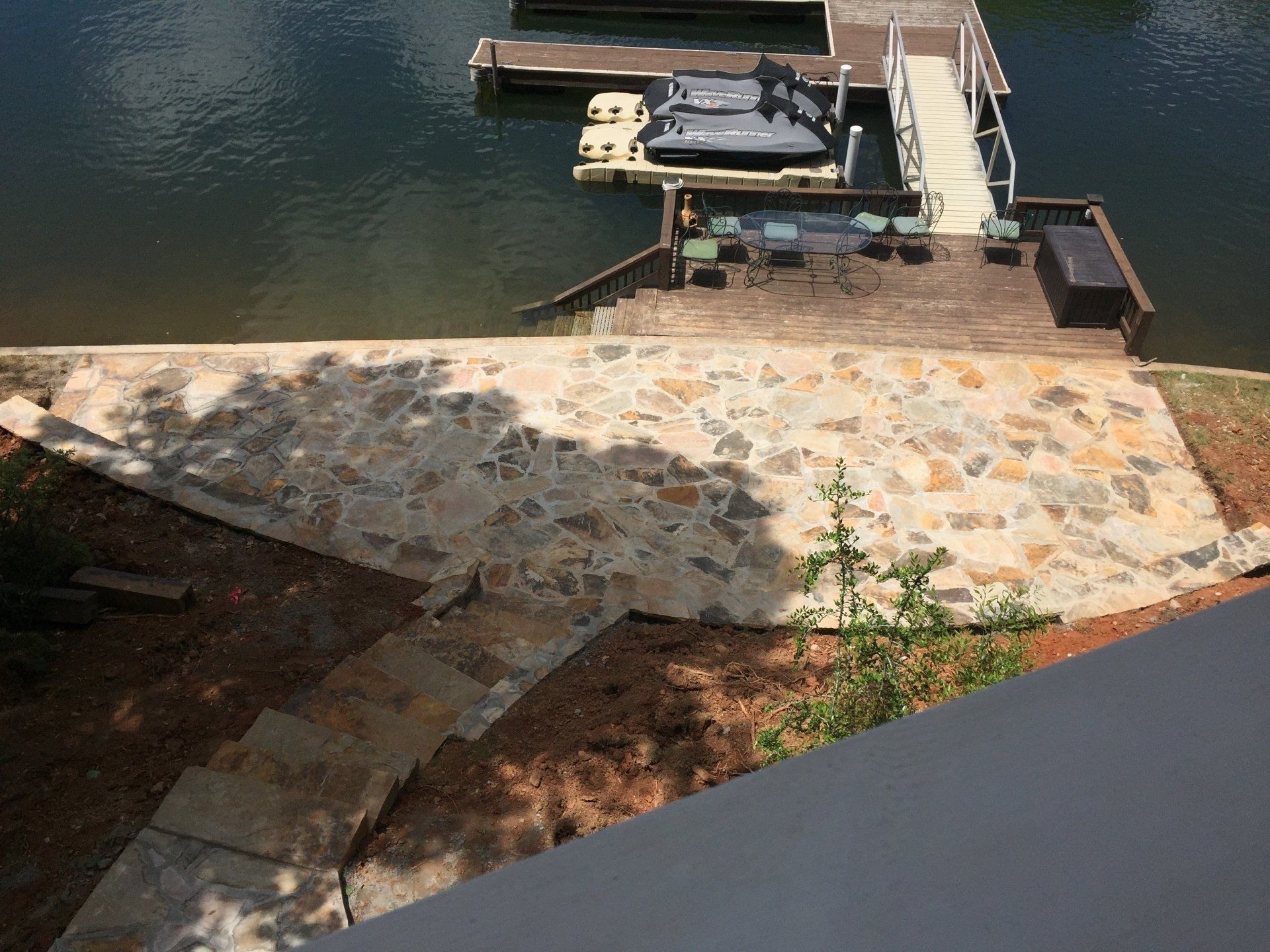 Stone patio with stairs leading down to a dock on a lake.