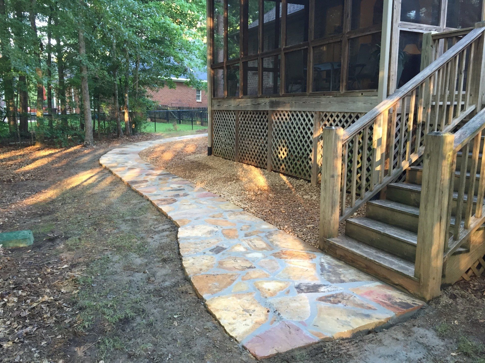Stone pathway leading to wooden steps and a screened porch.