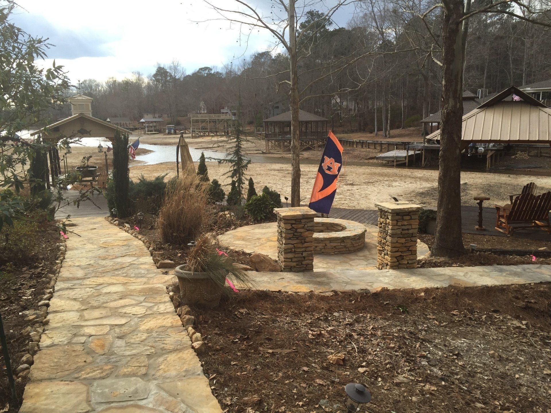 Stone path leads to a lake with a Clemson flag. Brown and orange colors dominate the setting.