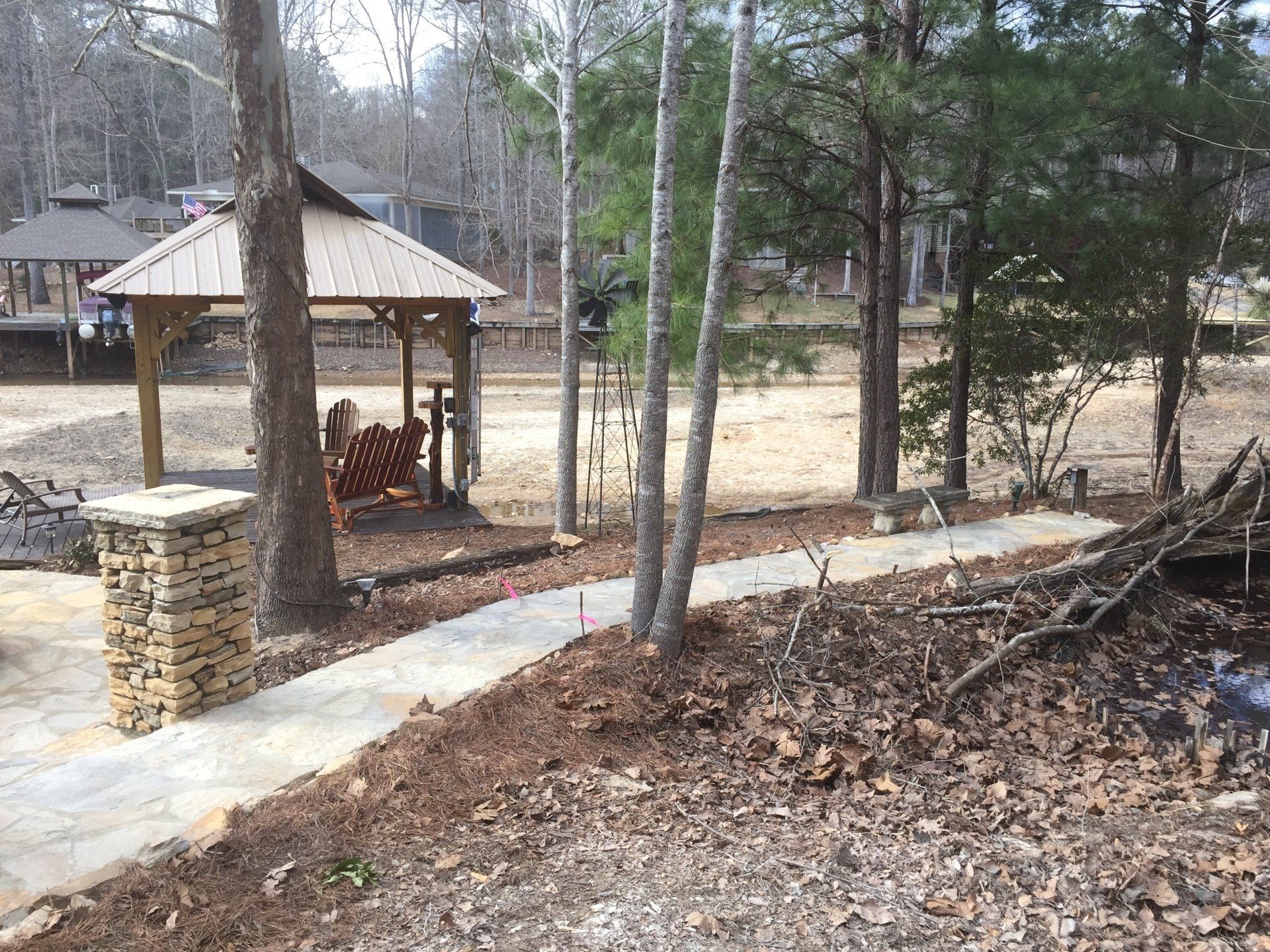Stone pathway leads to a gazebo near trees.