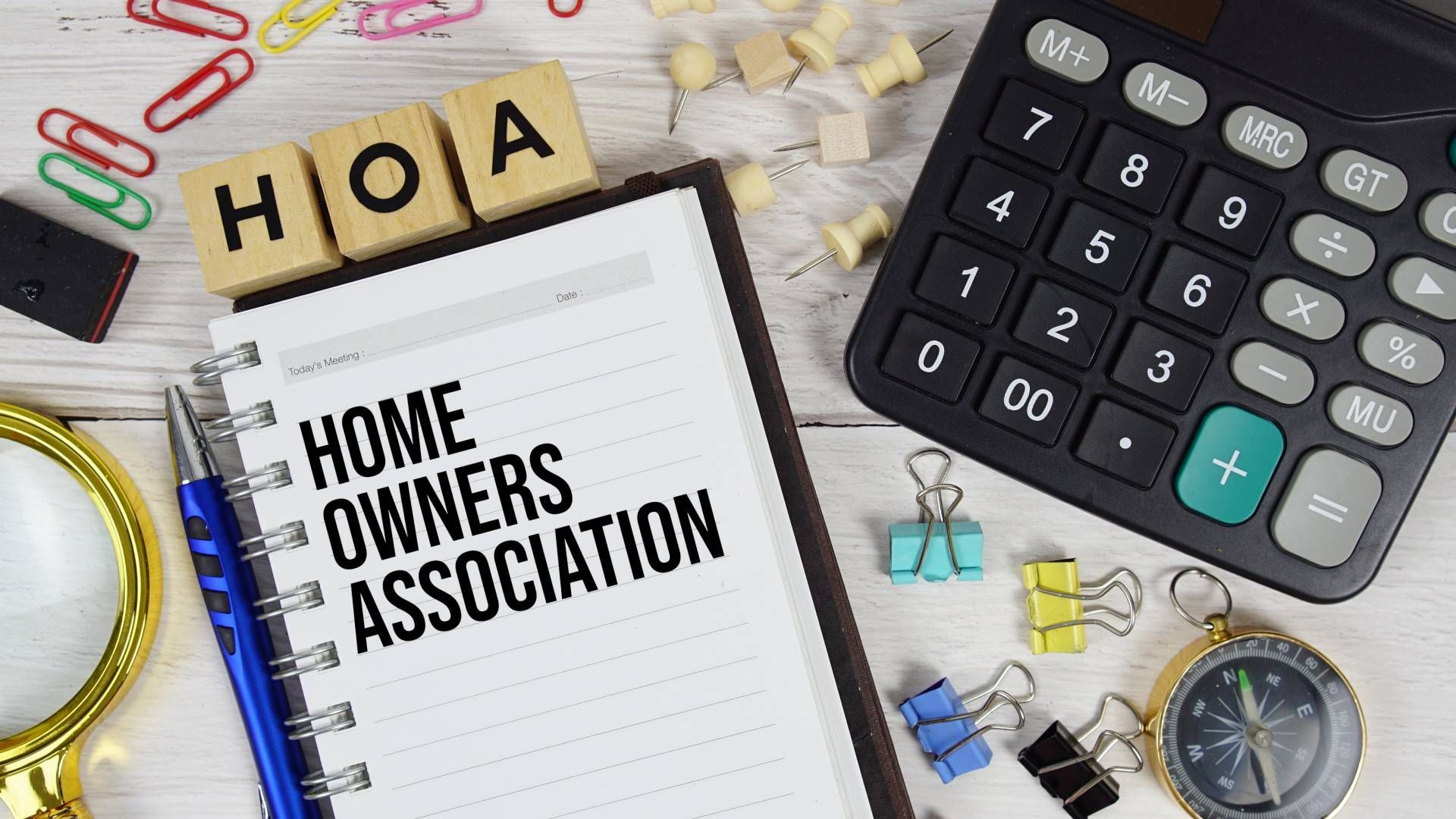 A notebook with the words `` home owners association '' written on it next to a calculator and a magnifying glass.