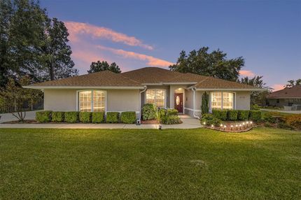 A white house with a brown roof is sitting on top of a lush green lawn.