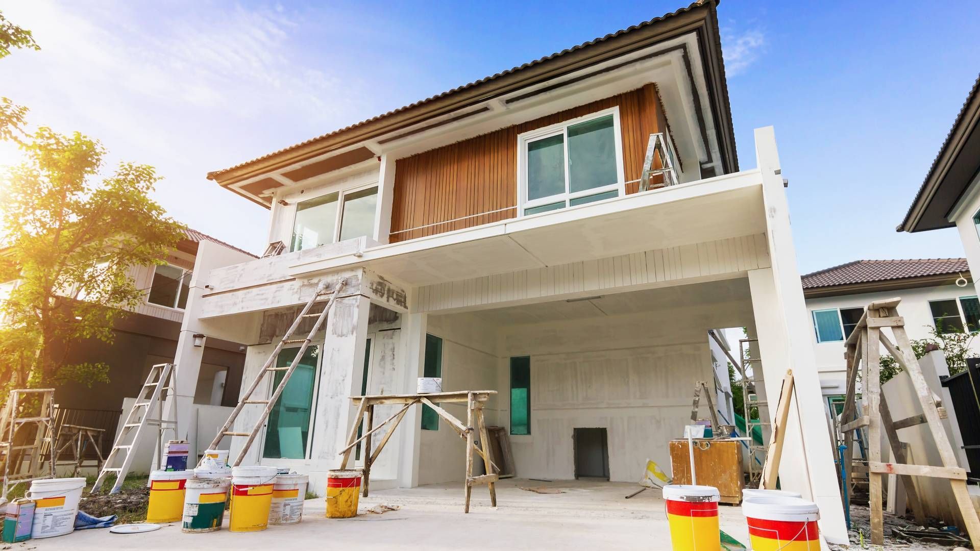 A house is being painted with buckets of paint and a ladder.