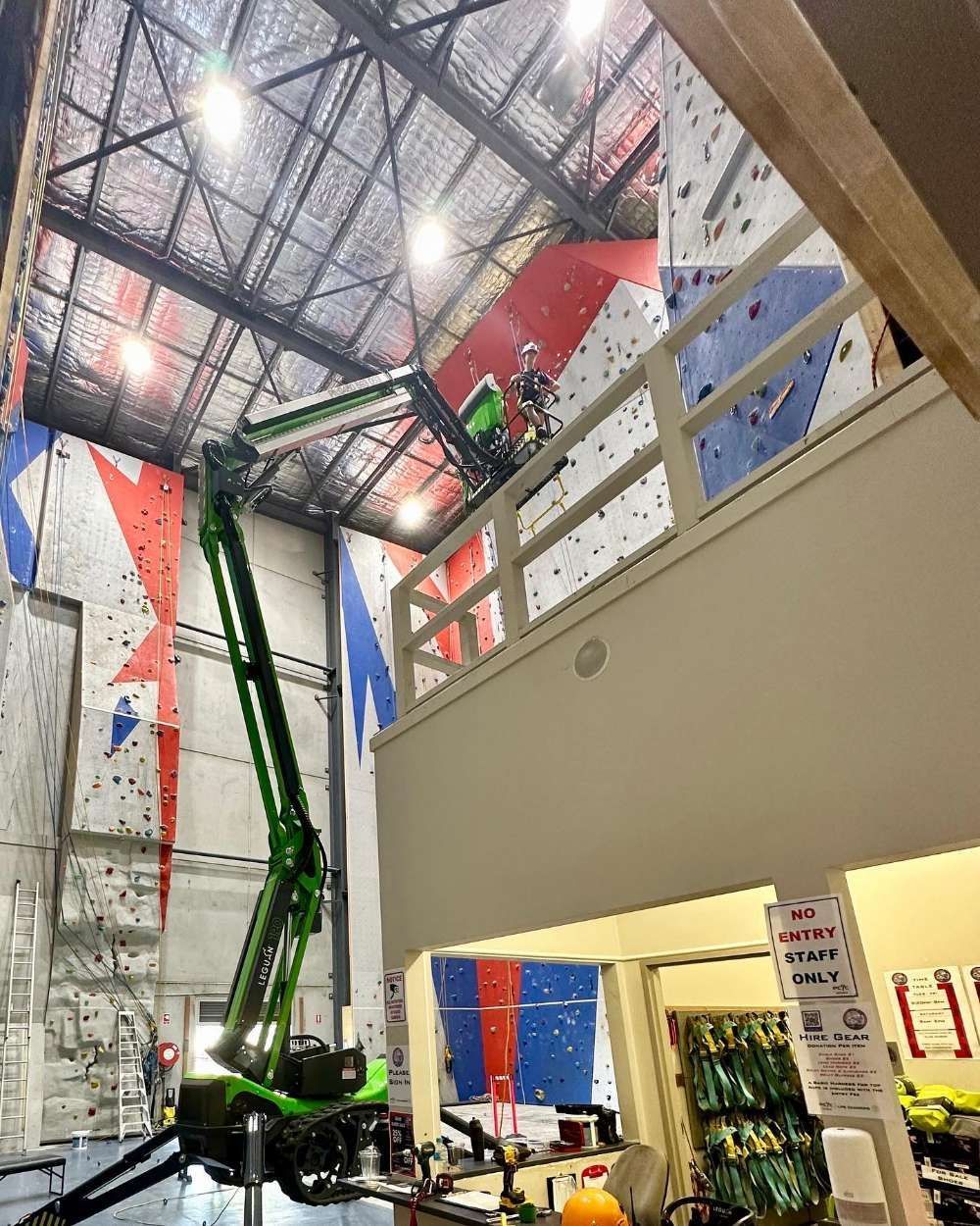 A Green Crane Is Working On A Climbing Wall In A Gym — High Work Services in Maitland, NSW