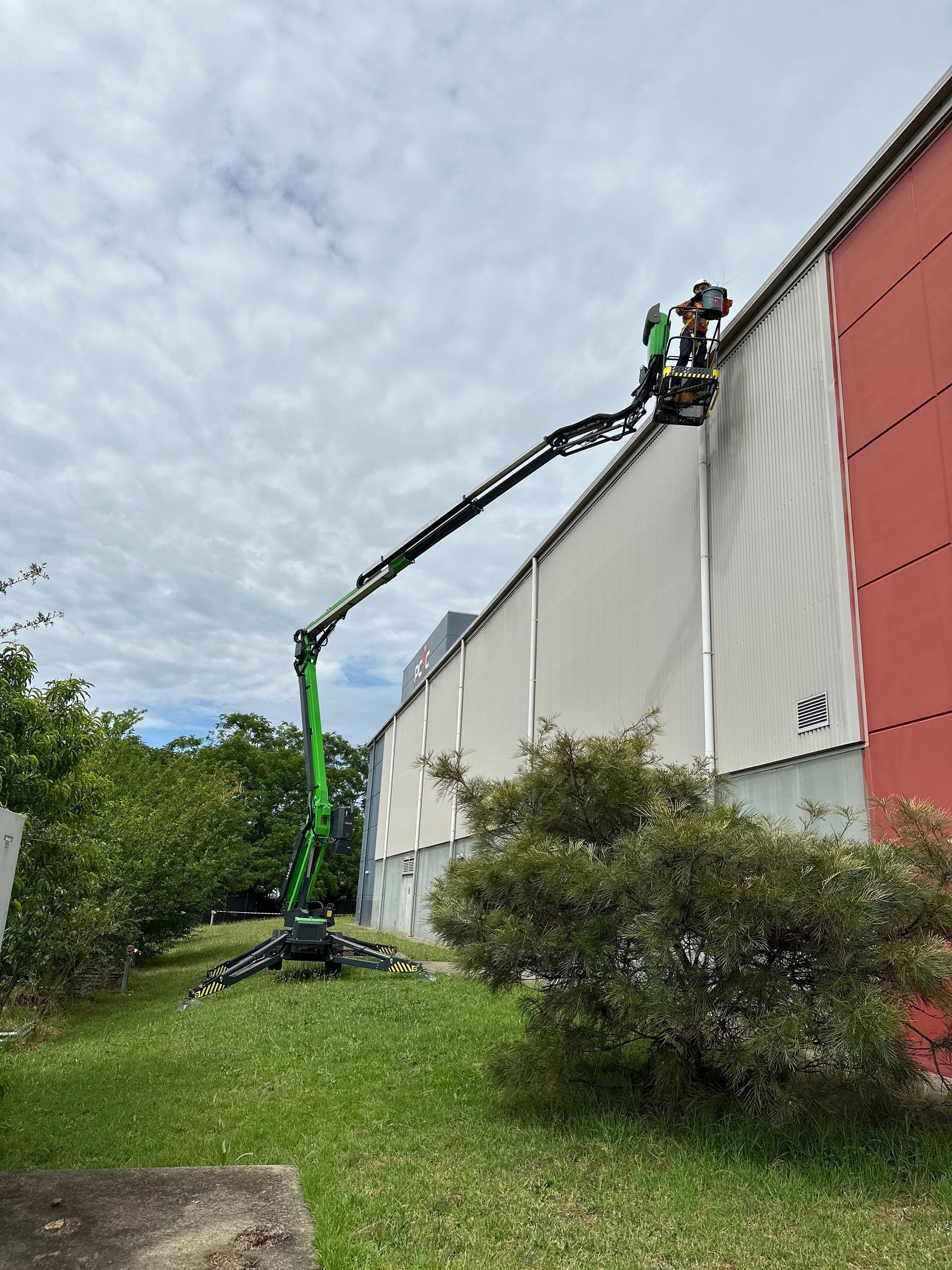A Green Crane Is Parked In Front Of Building — High Work Services in Central Coast, NSW