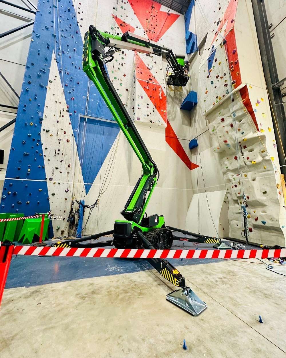 A Green Crane Is Sitting In Front Of A Climbing Wall — High Work Services in Maitland, NSW