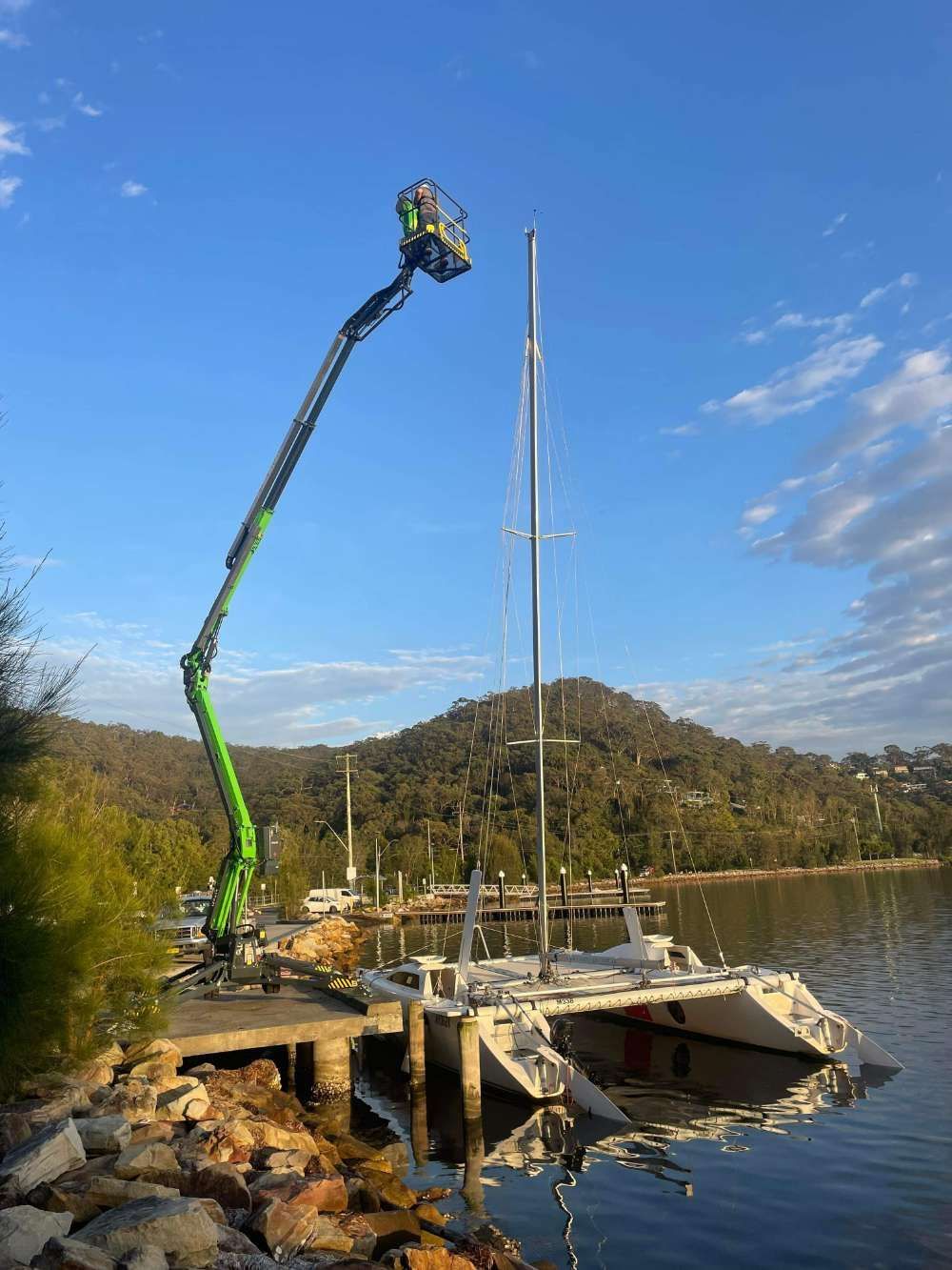 A Crane Is Lifting A Sailboat Into The Water — High Work Services in Maitland, NSW