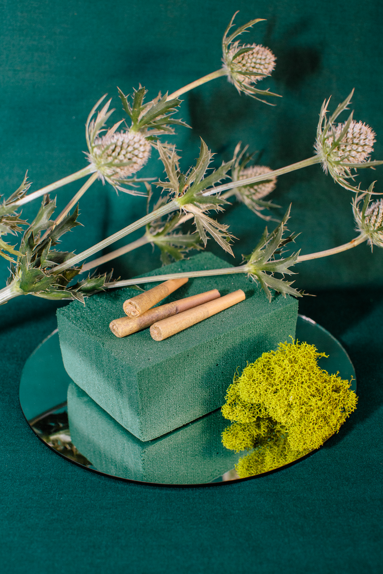 A bunch of flowers are sitting on top of a green foam block on a mirror.