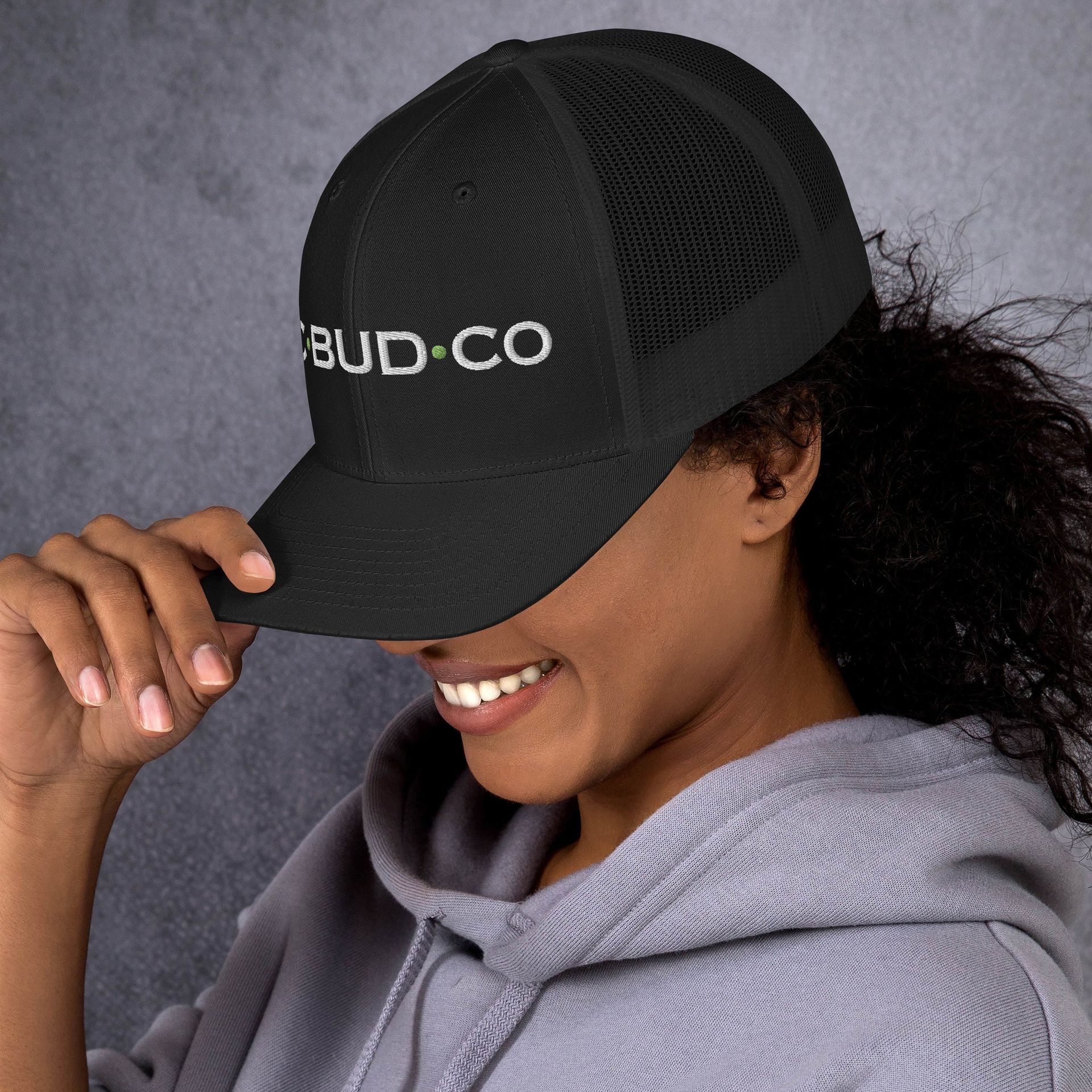 A woman wearing a black hat that says bud co on it