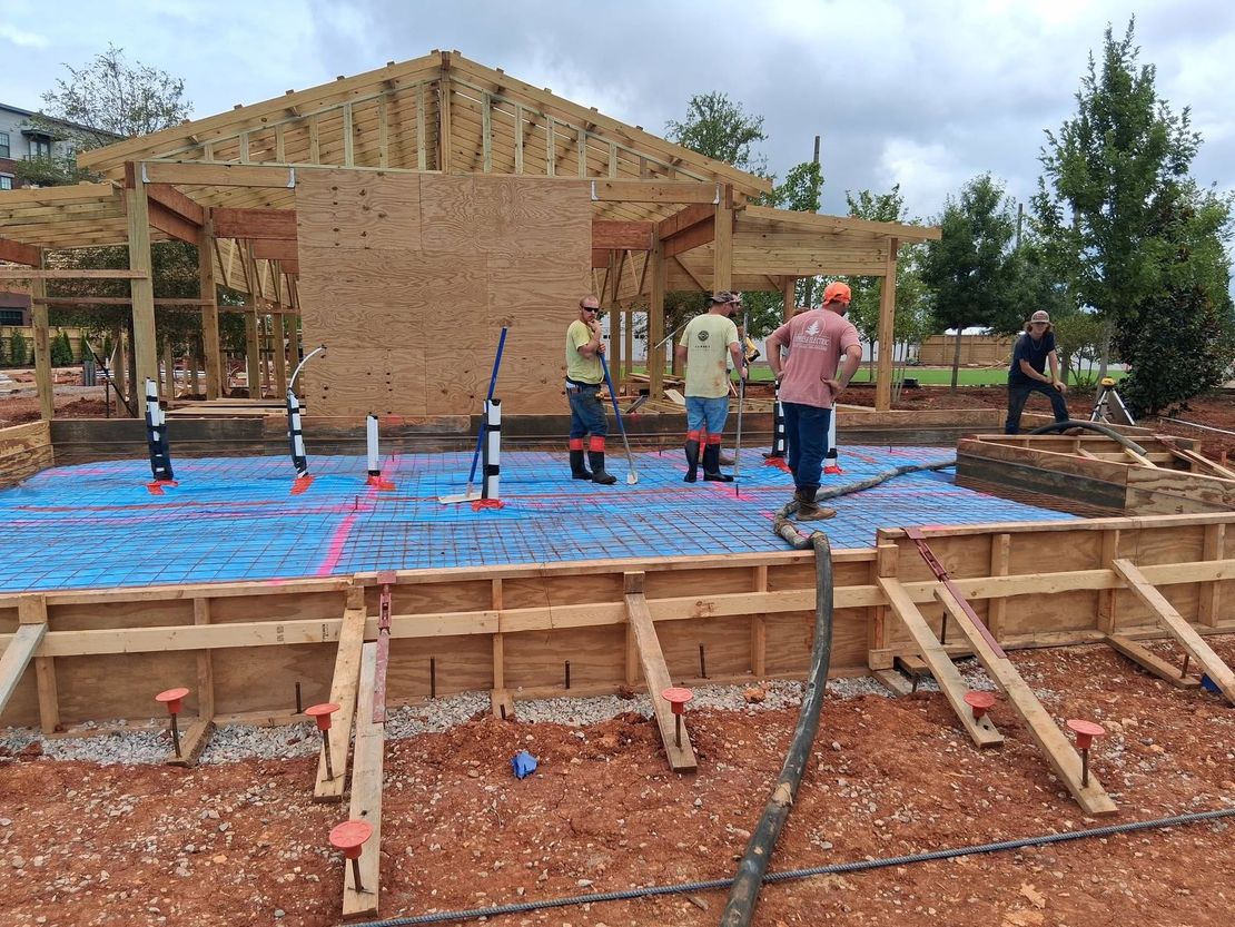 Workers building a house foundation with blue plastic sheeting and wooden framing at a rural site
