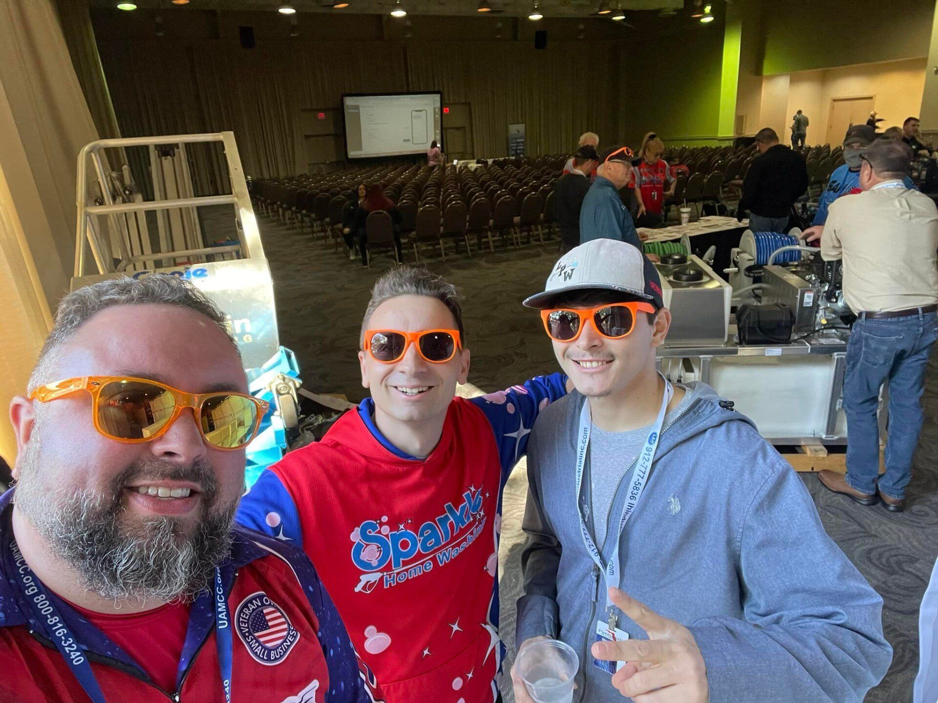 Three men wearing sunglasses are posing for a picture in a large room.