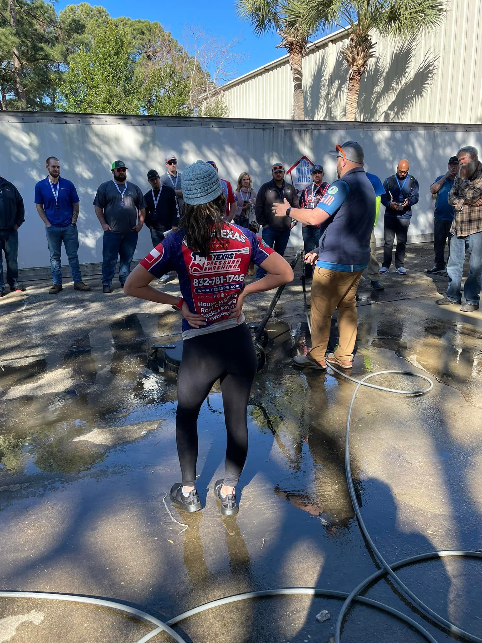 A woman is standing in a puddle of water in front of a group of people.