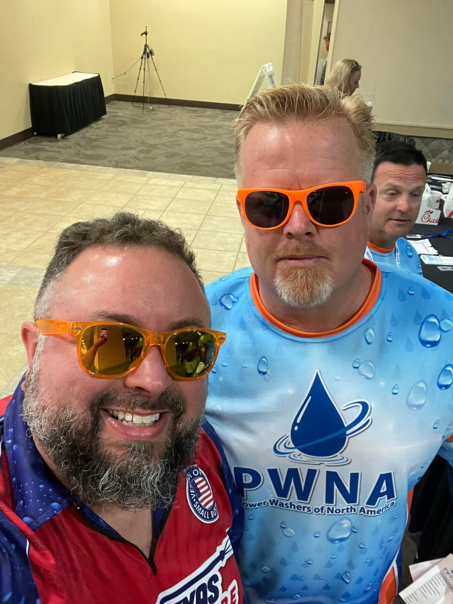 Two men wearing sunglasses and a shirt that says pwna are posing for a picture.