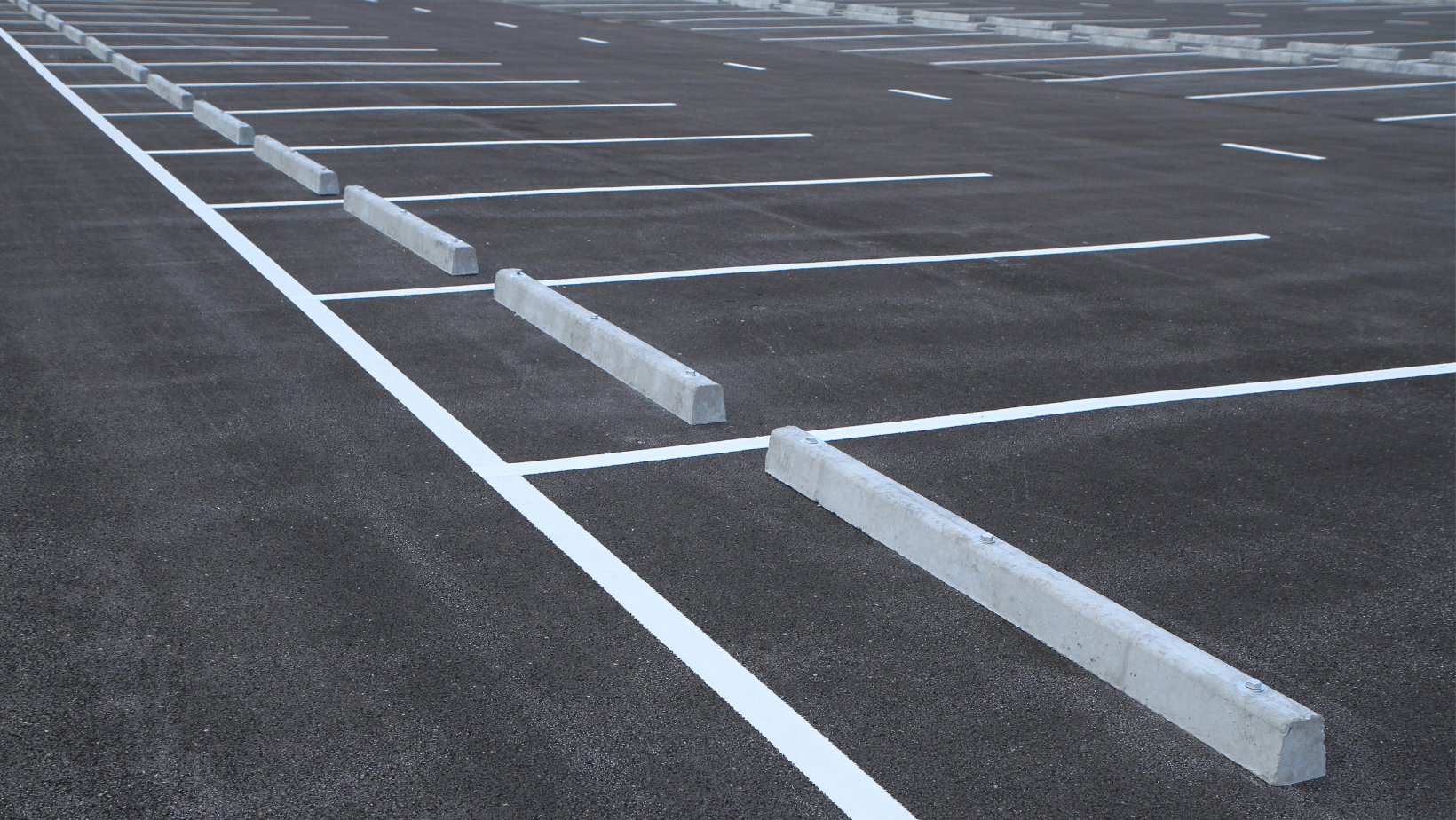 A parking lot with white lines and concrete curbs
