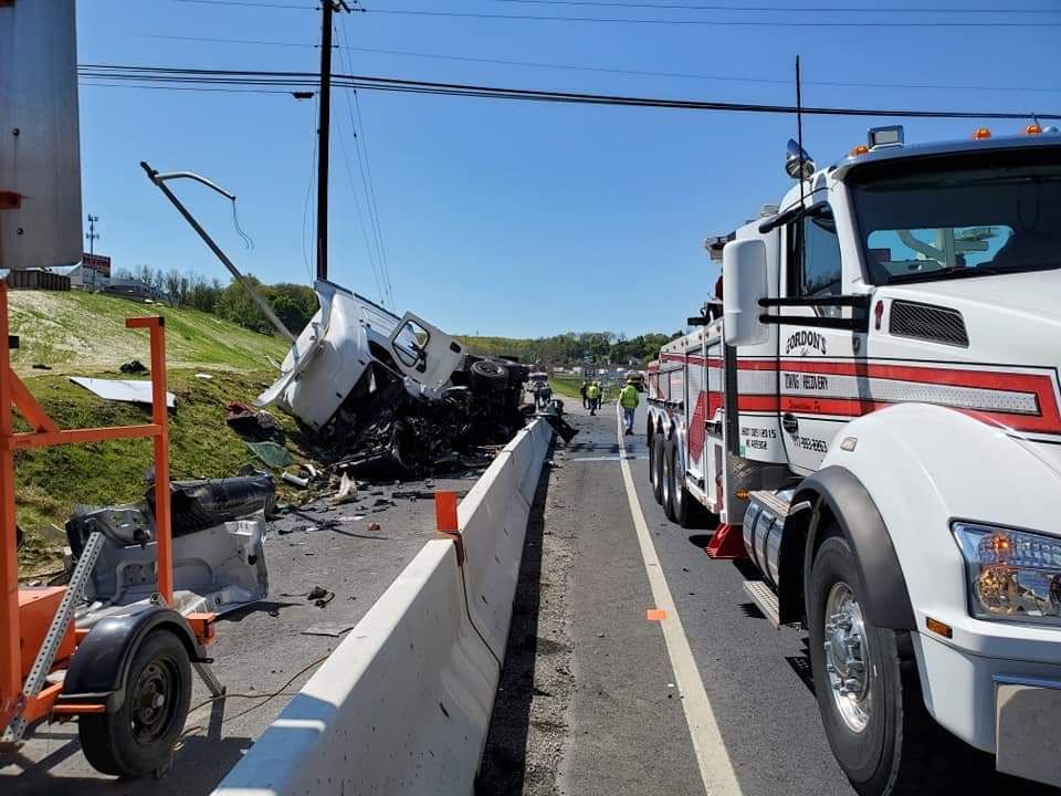 A row of tow trucks are parked on the side of a highway.