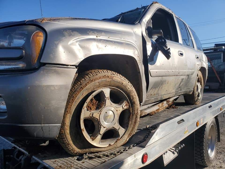 A car with a flat tire is sitting on top of a tow truck.