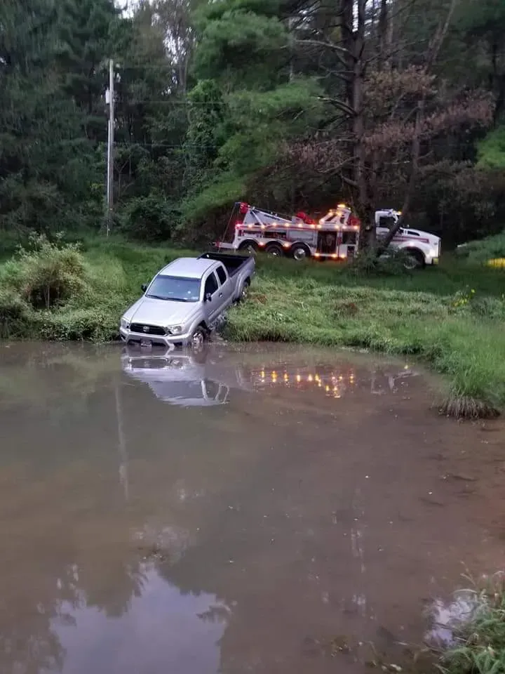 A white truck is stuck in a muddy pond.