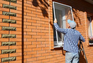 A Man is Installing a Mosquito Screen on a Window on a Brick Wall — Southside Glass & Aluminium In Bentley Park, QLD