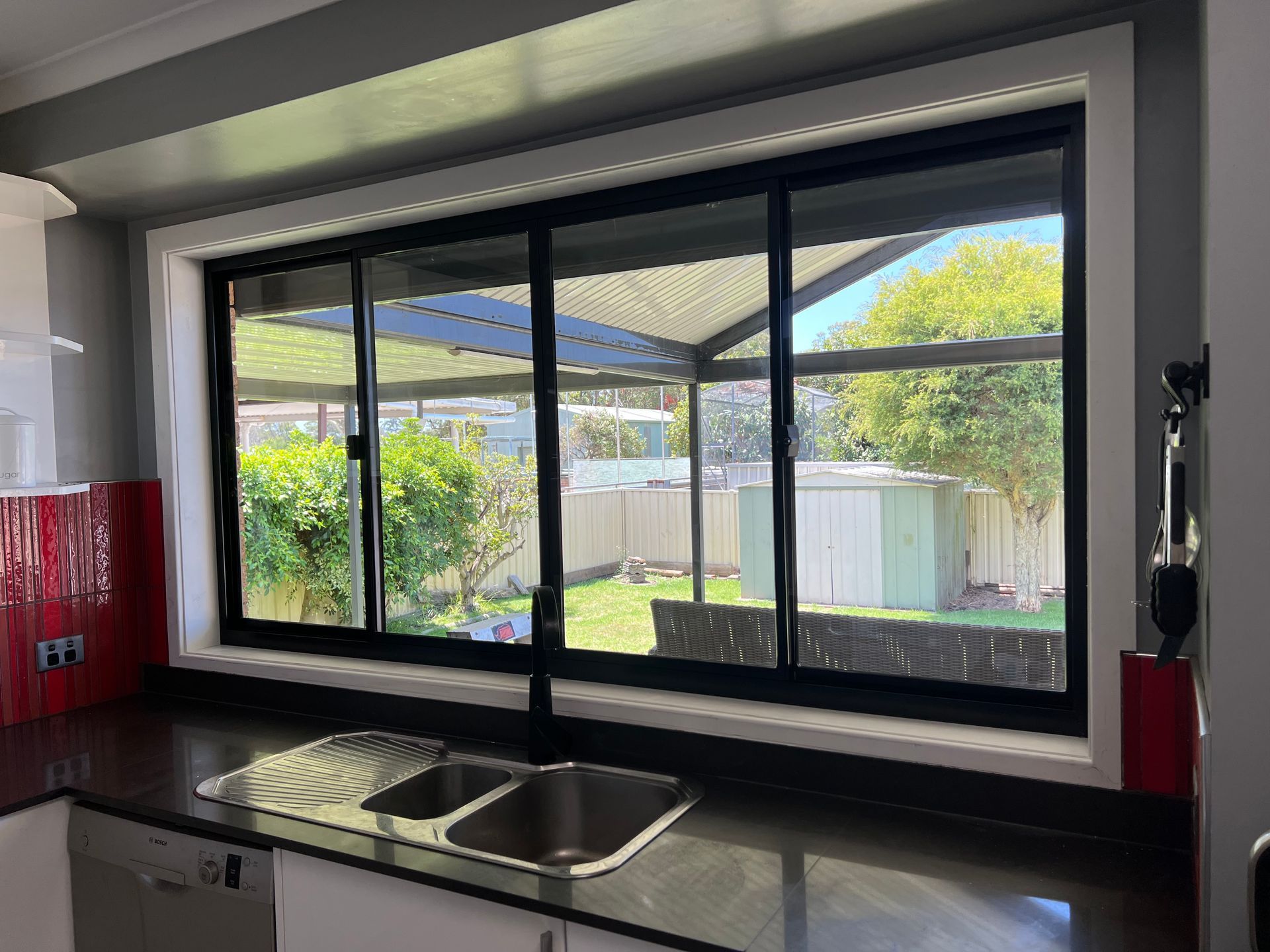 A Kitchen With a Sink and a Large Window With Sliding Glass Doors — Southside Glass & Aluminium In Bentley Park, QLD