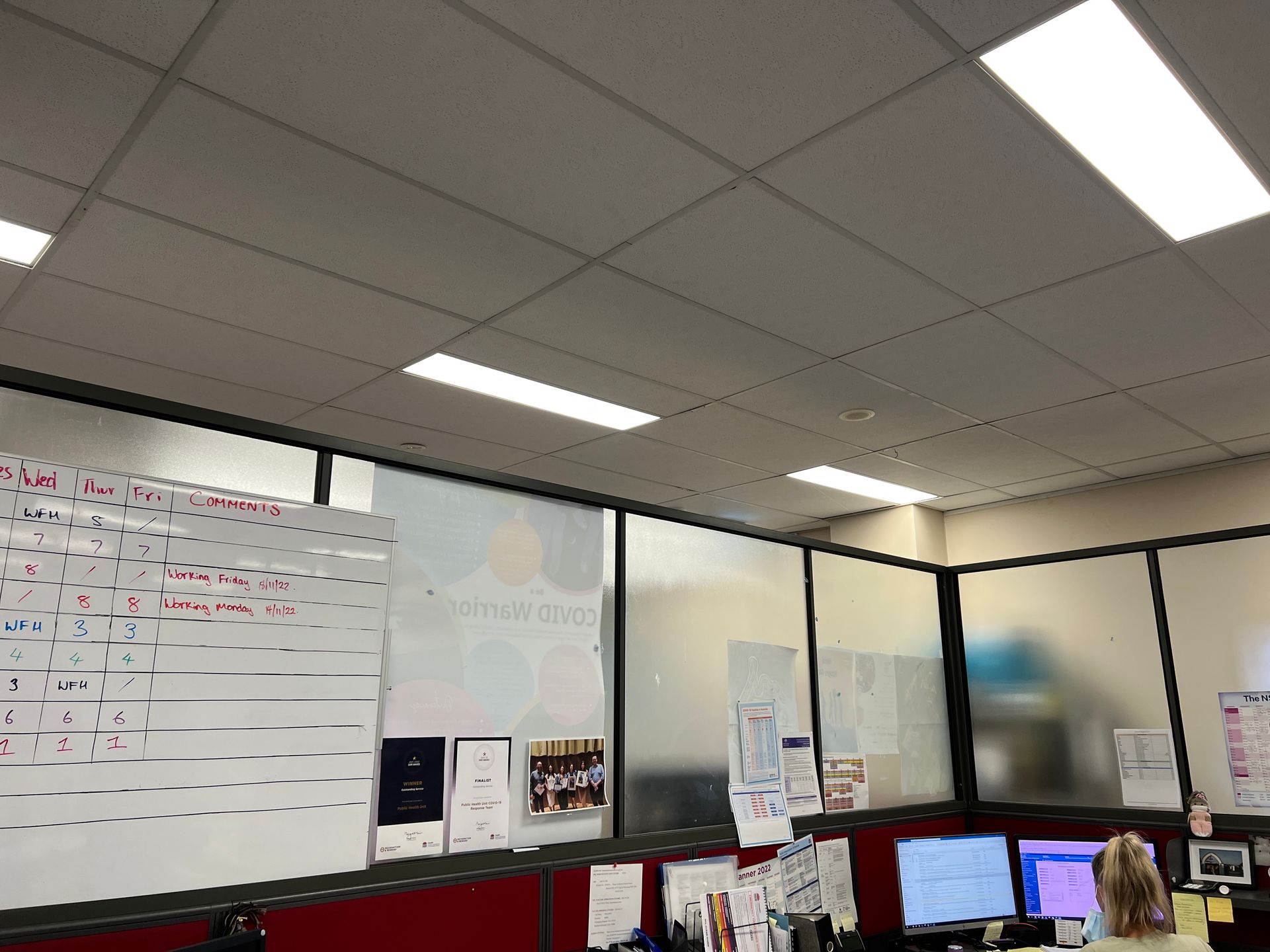 A Woman is Sitting at a Desk in a Cubicle in Front of a White Board — Southside Glass & Aluminium In Bentley Park, QLD