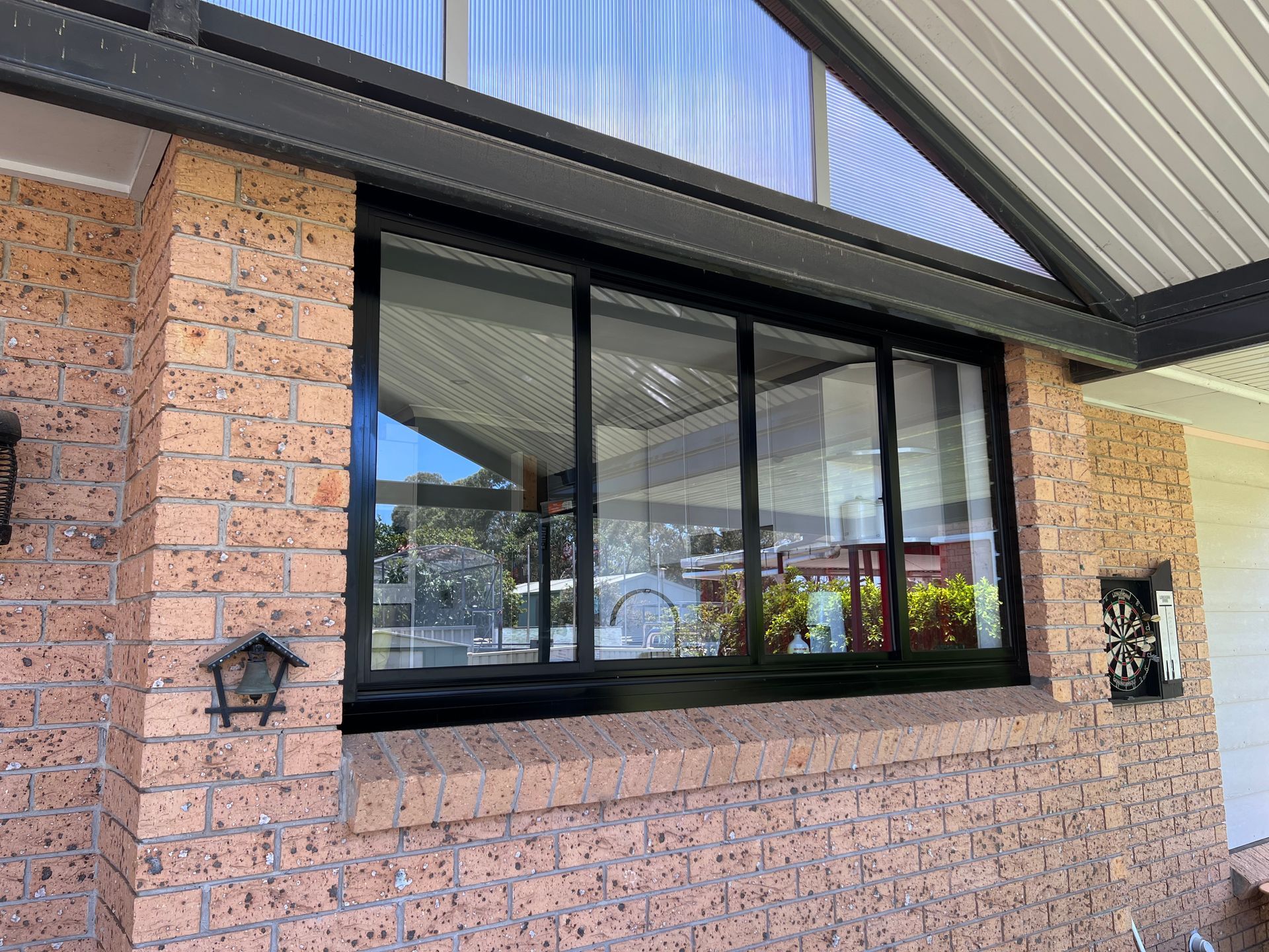 A Large Window on the Side of a Brick House With a Black Frame — Southside Glass & Aluminium In Bentley Park, QLD