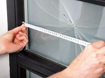 A Person is Measuring a Broken Window With a Tape Measure — Southside Glass & Aluminium In Bentley Park, QLD 