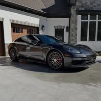 Dark gray sports car parked in a driveway outside a modern house