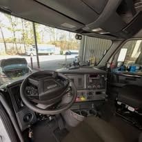 Truck cab interior with steering wheel, dashboard, and passenger seat visible
