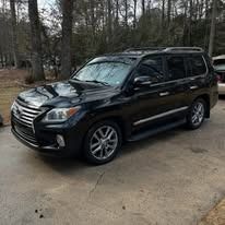 Black SUV parked on a wet driveway with trees in the background