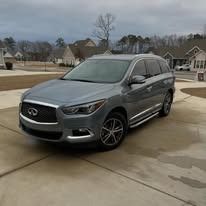 Gray Infiniti SUV parked on a driveway in a suburban neighborhood on an overcast day
