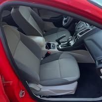 Red car interior with gray front seats and center console viewed from the side open door