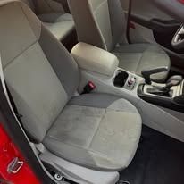 Gray front car seats and center console inside a red vehicle interior.