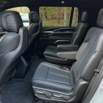 Empty black leather truck back seat with folded center armrest and dark interior