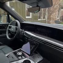 Modern car interior with steering wheel, large dashboard screen, and center console cupholders