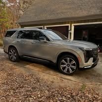 Silver SUV parked in a driveway beside a garage, with fallen leaves in the foreground.