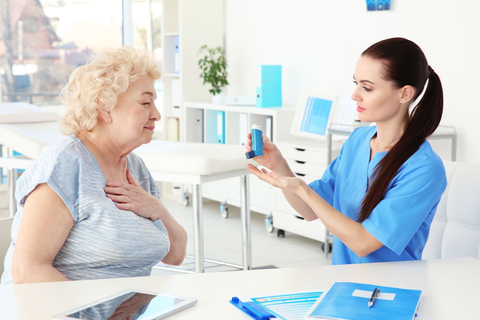 Doctor giving elderly woman inhaler in clinic