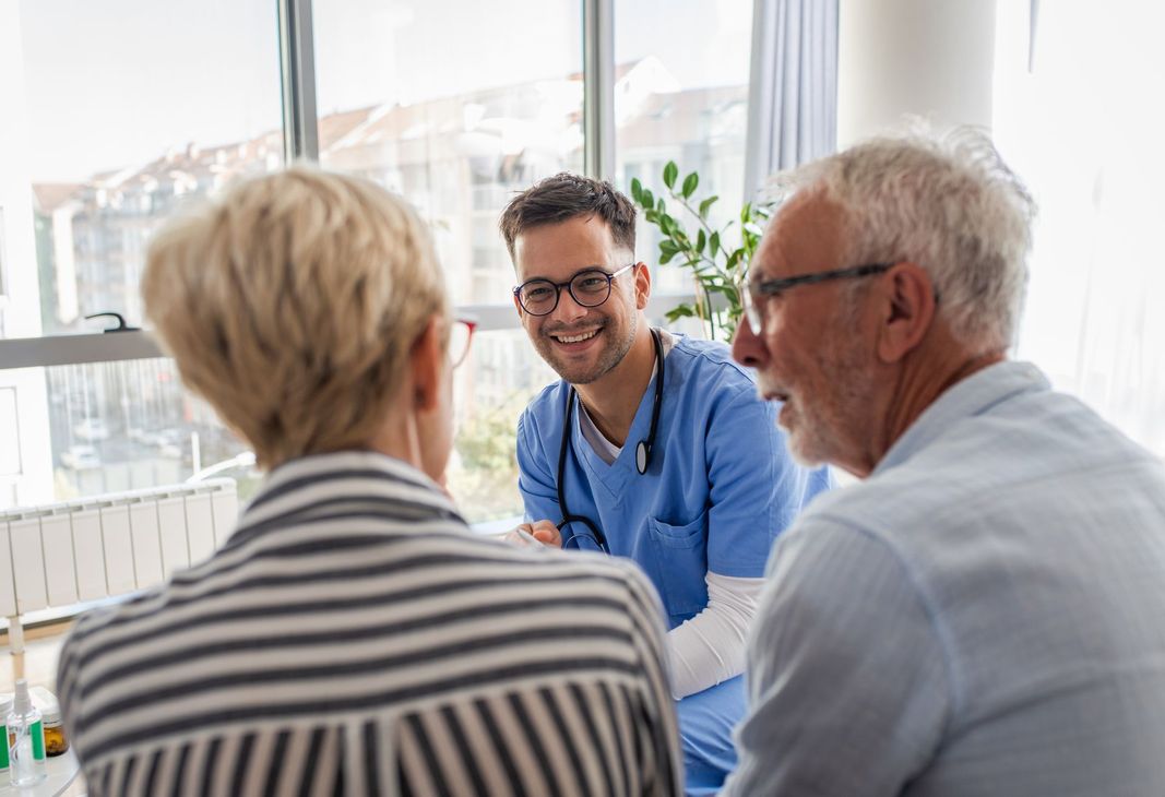 Male nurse talking to seniors patients while being in a home visit