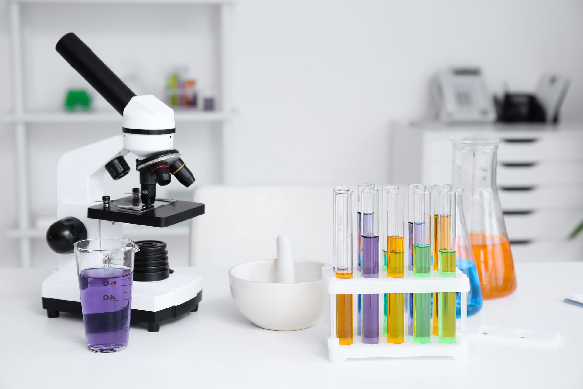Modern microscope and chemical glassware on table in medical laboratory